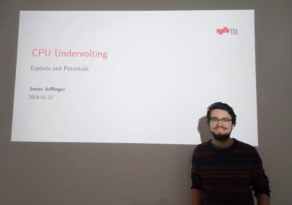 Jonas Juffinger is standing before the screen. On the screen the first slide of the presentation is displayed