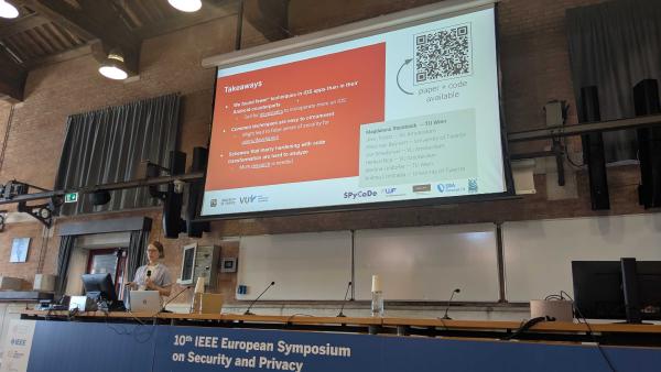 Magdalena Steinböck is presenting at the EuroS&P 2025 in a large lecture hall. A slide with logos and a QR code is projected on the screen, summarizing key points