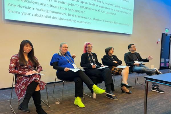 Photo of the iMentor Workshop panelists sitting in chairs on a stage, with Martina Lindorfer in the center of the group