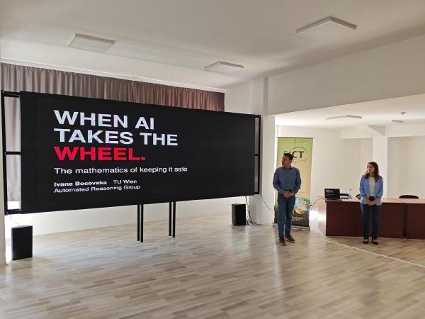 Ivana Bocevska of TU Wien presenting her lecture “When AI Takes the Wheel: The Mathematics of Keeping It Safe“ during European Researchers’ Night 2026, standing beside a large presentation screen