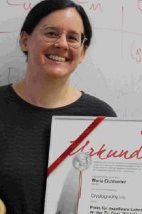 Maria Eichlseder standing before a whiteboard, holding an award 
